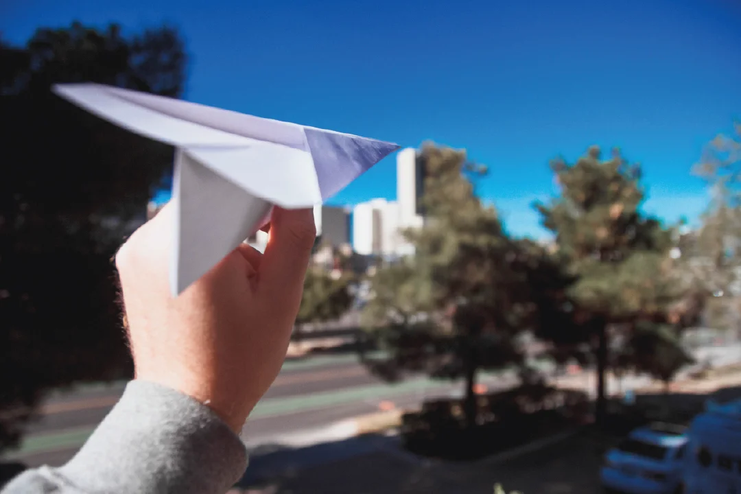 man's hand preparing to send a paper airplane into flight