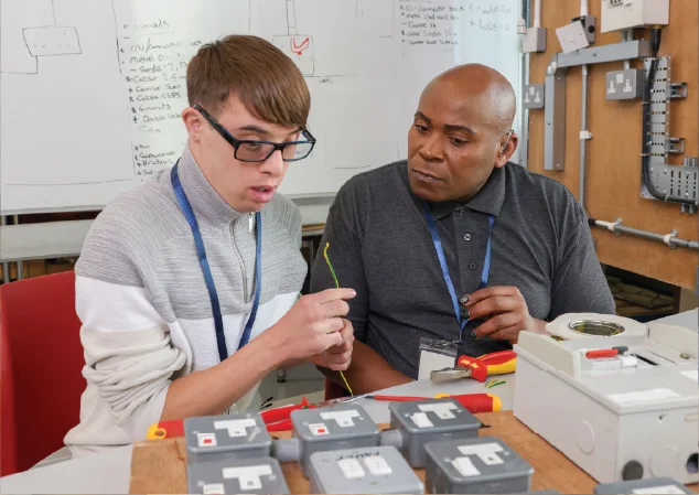 two young adult men working together on an electrical panel